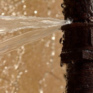 An old pipe has burst in winter, and water squirts out with lots of splashes